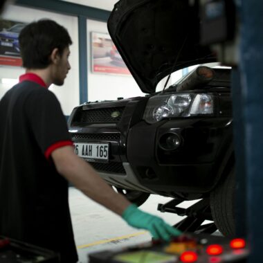 Mechanic using equipment to raise SUV for inspection in an automotive garage.