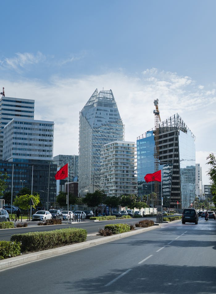 Urban skyline of Casablanca featuring modern architecture and Moroccan flags on a sunny day.