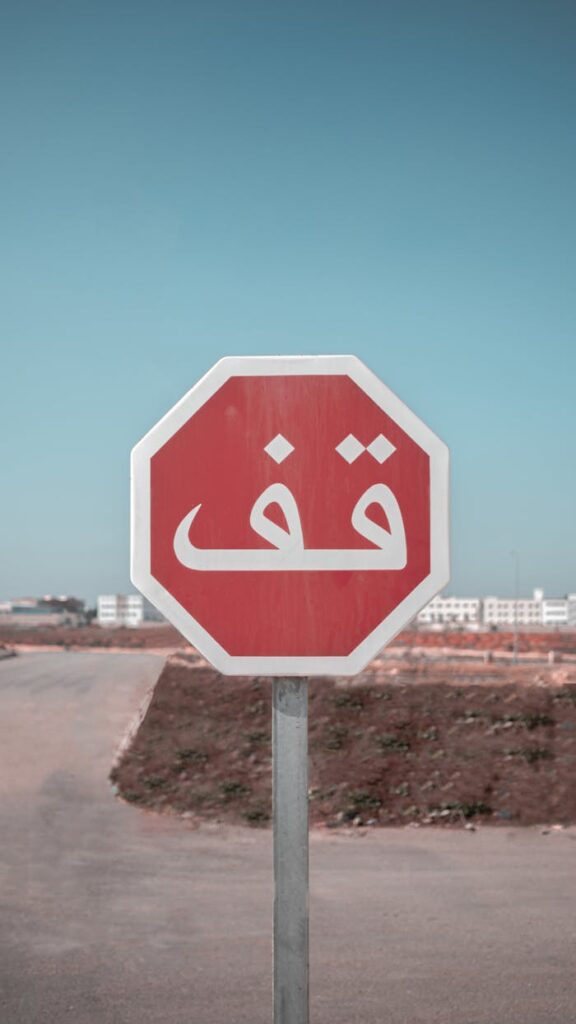 Red stop sign in Arabic on a road in Fes, Morocco, under clear skies.