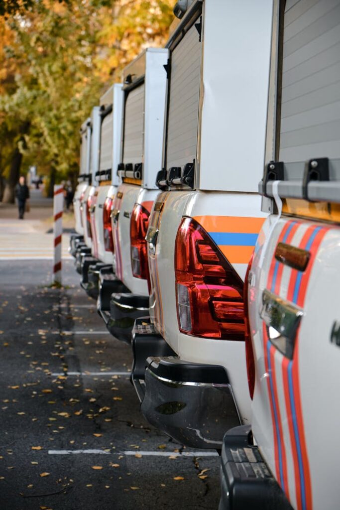 A row of pick-up trucks parked outdoors during autumn with falling leaves.